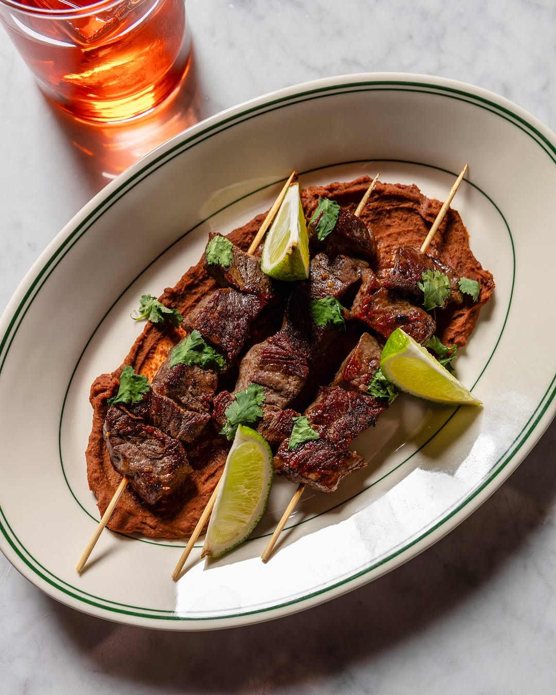 Beef skewers grilling over open flame on the Marrow patio