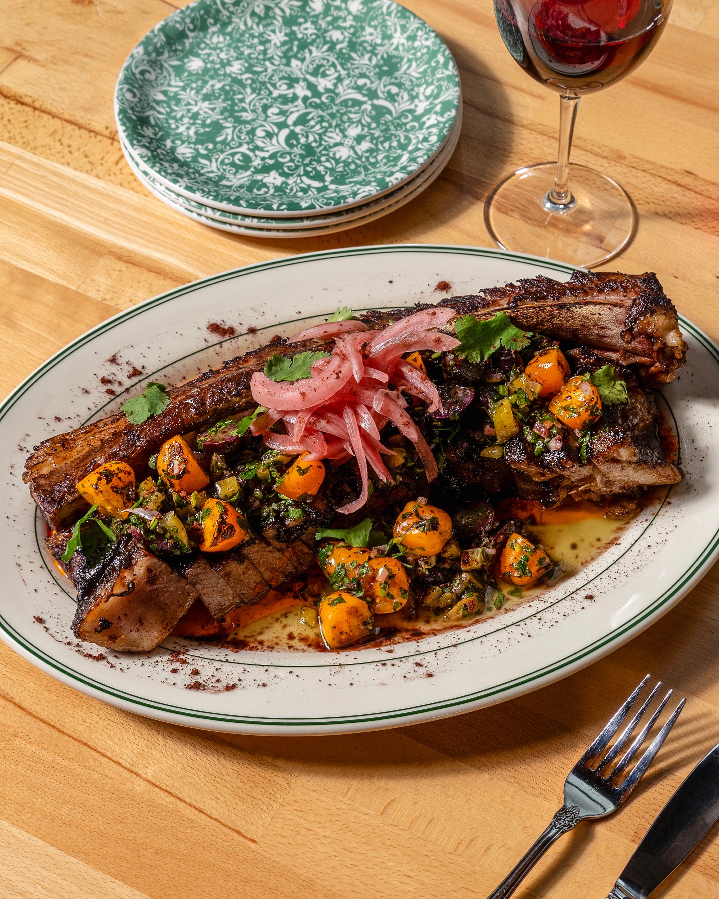 A roasted marrow bone plate with seasonal vegetables and a glass of red wine
