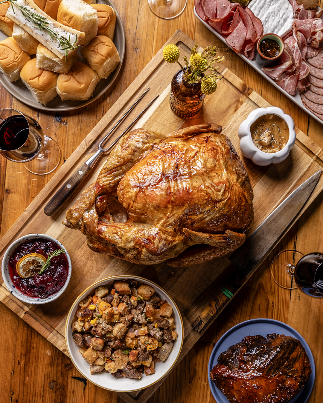 Roast turkey on a carving board with stuffing, cranberry sauce, and gravy