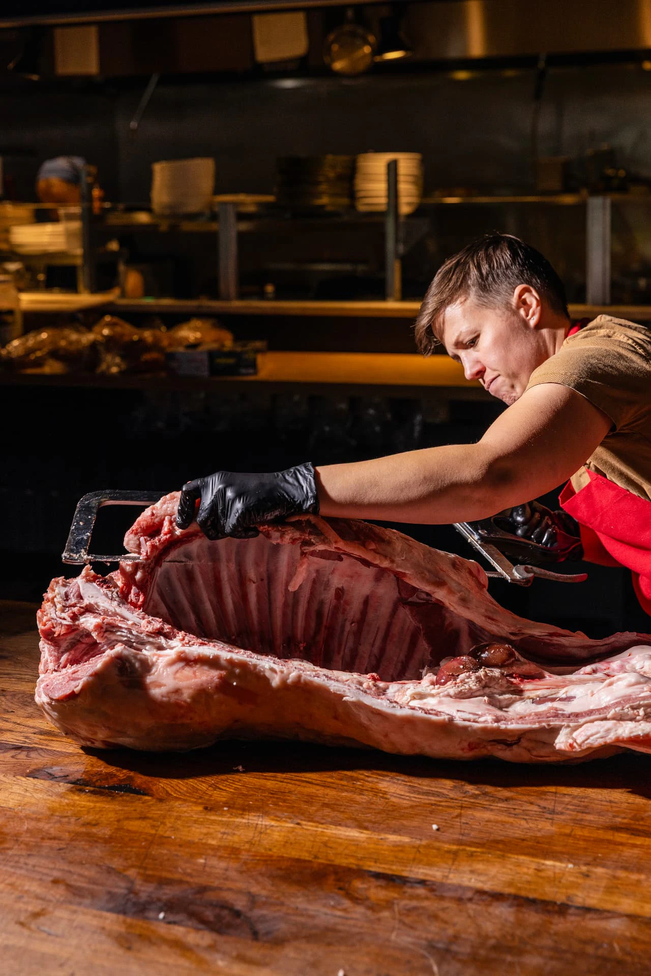 A Marrow butcher breaking down a large cut of meat on a butcher block